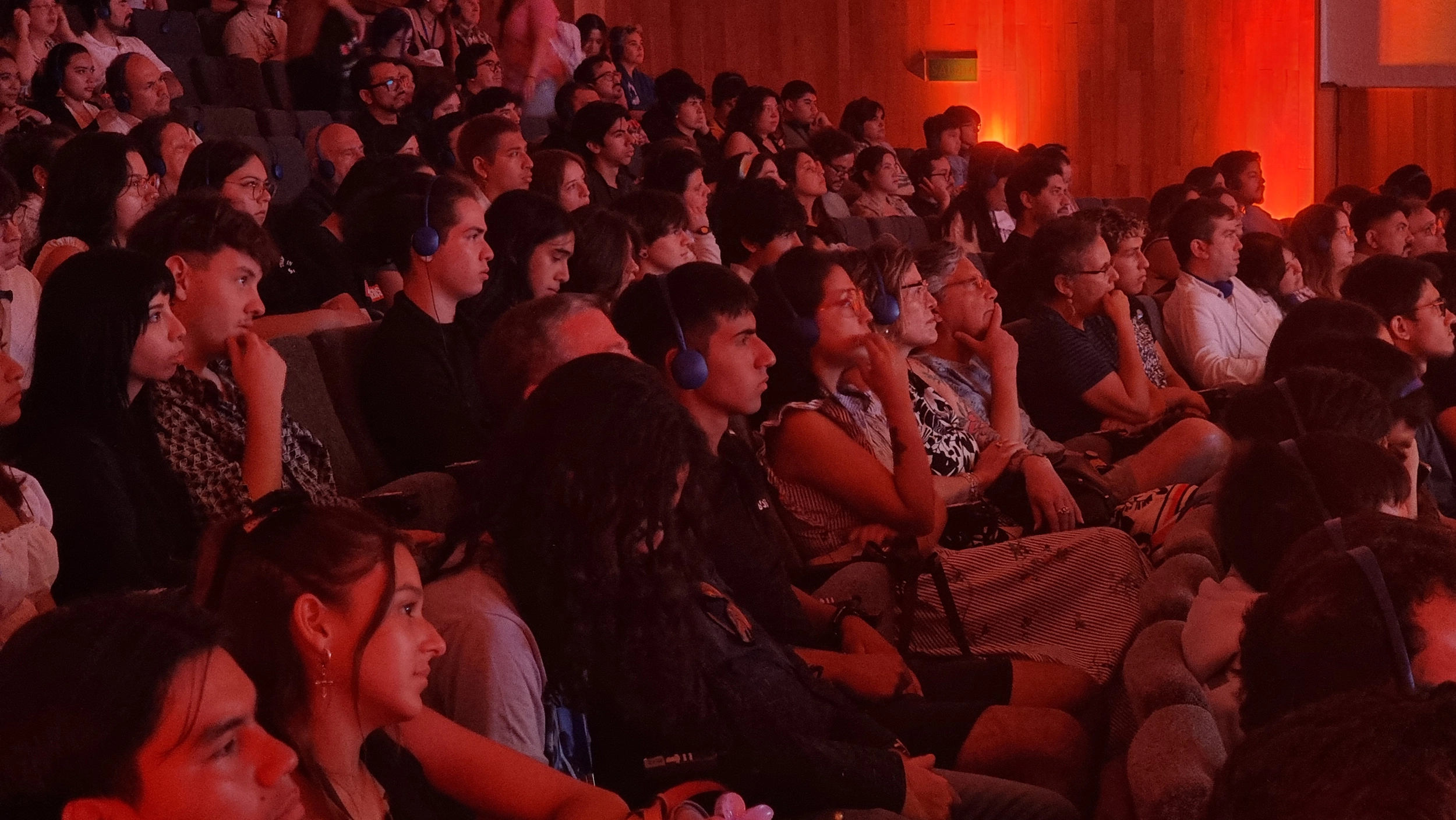 Público en un auditorio con iluminación roja de escenario
