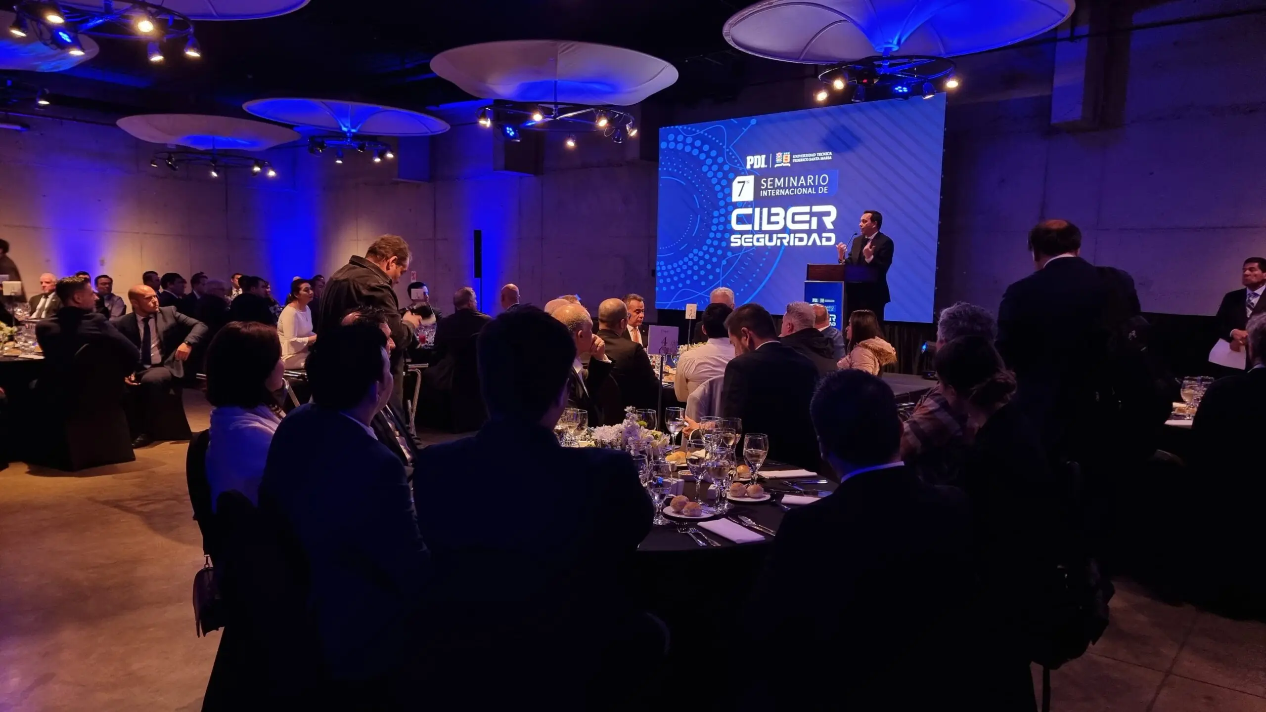 Cena corporativa con iluminación azul y pantalla de proyección